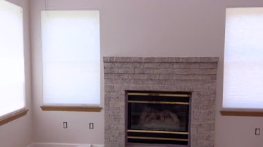 Görünür ahşap döşemeleri ve yeni bitirilmiş tuğlaları olan merkezi bir şömine manzarası. Kompozisyondaki simetri dengeli bir his ekler.