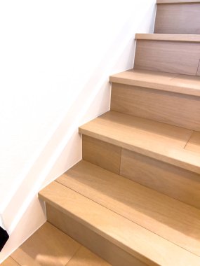 Hafif ahşap basamakları ve beyaz duvarları olan modern bir merdiven gösteriliyor. Temiz ve minimal tasarım çağdaş mimariyi vurguluyor.