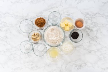 Düz yatıyordu. Limonlu haşhaş tohumlu kek pişirmek için cam karışımında ölçülmüş malzemeler..