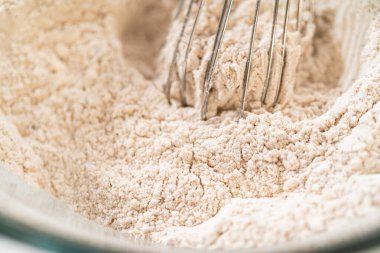 Baharatlı Zencefilli Kurabiyeli Kurabiye Hamuru 'nun kuru malzemelerinin yukarıdan görünüşü cam bir kasede çırpılmak için mükemmeldir. Un ve baharatlar bir araya getirilip, tek bir karışım oluşturulur.