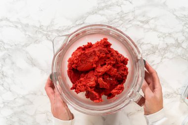 Klasik Kızıl Zencefilli Ekmek 'in canlı kırmızı hamuru tamamen karıştırılmış bir cam karıştırma kabında, derin rengini ve pürüzsüz dokusunu sergiliyor, pişirmeden önce soğutulmaya hazır..