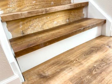 Tadilatın ortasındaki merdivenlerin bir bölümünde, merdivenler henüz kesilmemişken lamine lastik izleri görülüyor. Ahşap ton, yumuşak iç ışık altında beyaz büfelerle tezat oluşturuyor..