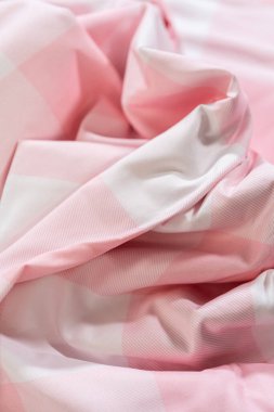 Yumuşak kıvrımlı ve açık gölgeli pembe ve beyaz pamuklu kumaş. Kırışık bir yüzeyde doku ve malzeme kalitesini yakalar.