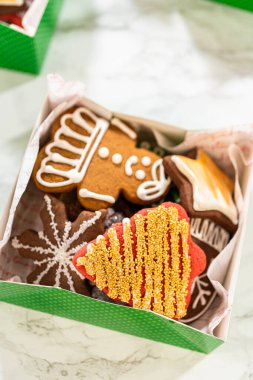 Yakın plan bir perspektiften yakalanan yeşil tatil hediye kutuları süslenmiş Noel kurabiyeleriyle dolu parşömen kağıdıyla güzelce düzenlenir. Festivalde eldiven, ağaç ve yıldız çeşitleri yer alıyor.