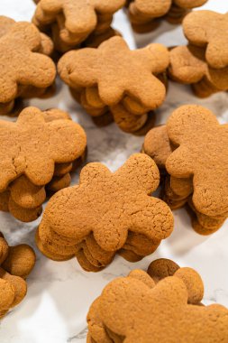 A stack of freshly baked gingerbread man cookies, highlighting their golden-brown color and classic holiday shape, ready for decorating.