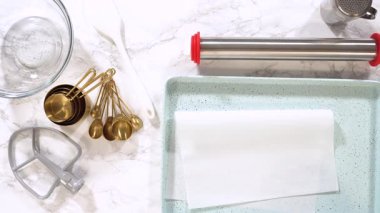 Eller, mutfak aletlerinin yanında turkuaz benekli fırın tepsisi ve parşömen kağıdı ile doluyor. Pişirme dersleri, aşçılık adımları ve mutfak hazırlıkları için harika..