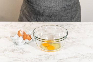 Mermer tezgahın üzerine yerleştirilmiş yumurta ve akçaağaç pekmezli küçük bir cam kasenin önü. Çikolata, zencefilli kurabiye ve çörek karışımına eklenmeye hazır..