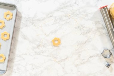 Un kaplı mermer tezgahın üzerine yerleştirilmiş tek çiçekli kurabiye hamuru. Paskalya Kurabiyesi Sandviçi 'nin ahududulu tereyağı kremalı tarifi..