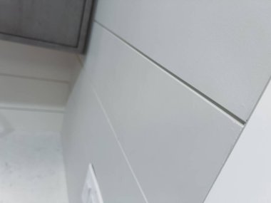 Temiz beyaz süslemeli ve modern gri panelli bir oda duvarının açılı görüntüsü. Resim minimalist ev tasarımı ayrıntılarını yakalar.