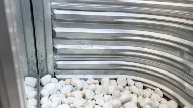 Evin bodrum penceresinin bir köşesinde metal kaplamalara karşı alt kısmı dolduran beyaz kayalar var. Işık yukarıdan girer.