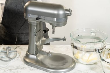 Bir karıştırma kabına krema için birkaç kalıp tereyağı yerleştirildi. Tarif adımları, yemek hazırlama kılavuzları ya da pişirme dersleri için ideal.