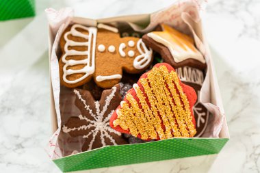 Yakın plan bir perspektiften yakalanan yeşil tatil hediye kutuları süslenmiş Noel kurabiyeleriyle dolu parşömen kağıdıyla güzelce düzenlenir. Festivalde eldiven, ağaç ve yıldız çeşitleri yer alıyor.