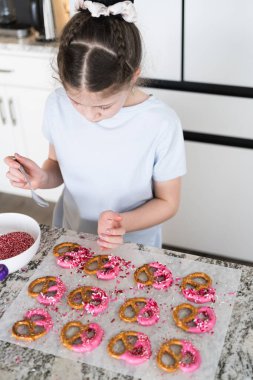 Odaklanmış bir dikkatle, bu filizlenen aşçılık sanatçısı krakerleri erimiş çikolataya batırarak iyi aydınlatılmış bir ev mutfağının sıcaklığında tatlı tatlar yaratıyor..