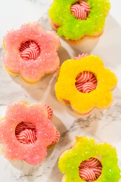 Ahududu kremalı Paskalya Kurabiyesi Sandviçi. Çiçek şeklinde bir şekerli kurabiye pembe ahududu kreması ve köpüklü şekerle kaplıdır. Tam oldu.