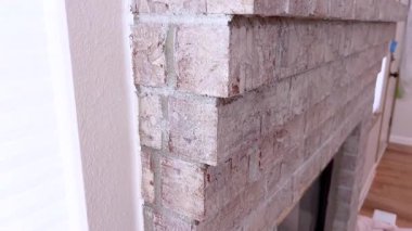 Şömine köşesinin yan profil videosu, katmanlı tuğla dokusu, boya boyası ve hizalama. Sahne yumuşak ve temiz..