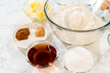 İçinde un, tereyağı, yumurta, esmer şeker, akçaağaç şurubu, kakao ve baharat bulunan Ginger Şekerli Kurabiye Hamuru 'nun içeriğinin tamamı mermer bir yüzeye yerleştirilmiş..