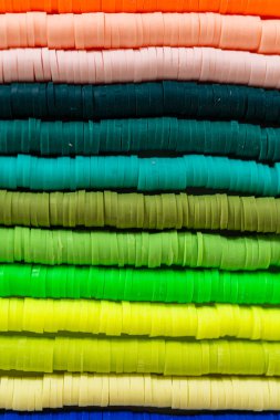 Beyaz bir masadaki renklere göre düzenlenmiş canlı bir kil boncuk koleksiyonu genç zanaatkarlara kendi eşsiz bileziklerini yapmaları için ilham vermeye hazır..