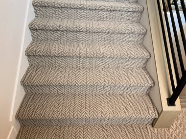 Şevron halısının yakın plan çekimi üst katta merdiven boşluğuyla buluşuyor. Halı kurulumu ya da merdiven tasarımı fikirleri için kullanışlı.