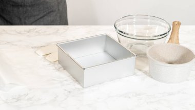 Kare alüminyum fırın tavası, cam karıştırma kabı ve mermer tezgahta pişirme hazırlığı için seramik havan ve tokmak seti..