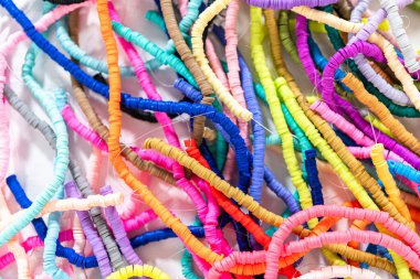 Beyaz bir masadaki renklere göre düzenlenmiş canlı bir kil boncuk koleksiyonu genç zanaatkarlara kendi eşsiz bileziklerini yapmaları için ilham vermeye hazır..