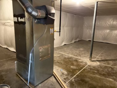 Parker, Colorado, ABD-1 Haziran 2025 - Beton döşeme ve beyaz yalıtımlı temiz bir emekleme alanı merkezi havalandırma ünitesini kanal işçiliğiyle kapatır. Mekanik sistem ısıtma ve hava için kurulur