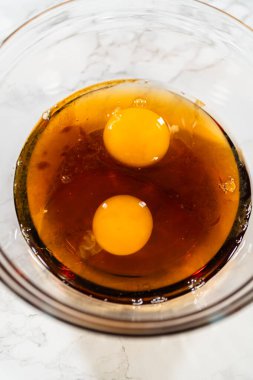 İki büyük yumurta cam bir kaseye kırılıp pekmez ile birleştirilmiş. Bu karışım, klasik kızıl zencefilli çöreğe zenginlik, nem ve lezzet katar..