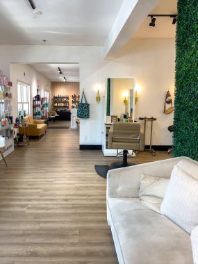 Parker, Colorado, ABD-3 Temmuz 2025 - Sahte yeşil duvar, krem koltuk ve açık ahşap döşeme içeren modern kuaför salonu alanı. Yumuşak ışıklandırma rahat ve şık bir hava yaratır. Boşluk...