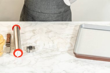 Mermer tezgahın üzerine sarılı hamurun yanına yerleştirilmiş mermer raptiye ve kurabiye keskisi. Ürün listeleme, pişirme hazırlık görselleri veya eğitim içeriği için mükemmel.