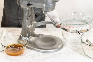 Karıştırma kabında Amber Zencefilli Kurabiye Hamuru 'nun malzemelerinin bulunduğu bir tezgahın yan görüntüsü, mermer tezgahın üzerine yerleştirilmiş, yakınlardaki ıslak malzemelerle dolu ayrı bir kase,