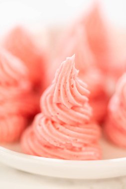 Yedi pipo şeklinde ahududu kreması beyaz bir tabakta, ahududu kremalı Paskalya Kurabiyesi Sandviçi için güzelce hazırlanmış. Tarif blogları, özel dersler ya da krema ilham kaynakları için harika..