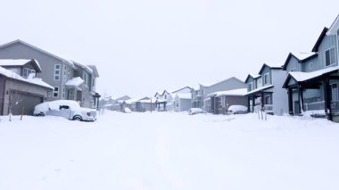 Castle Rock, Colorado, ABD-14 Mart 2024-Ağır çekim sahnesi, karla kaplanmış bir cadde boyunca uzanan ve kış boyunca uzanan berrak bir patikayla noktalanmış evlerle banliyö sükunetini tasvir ediyor.