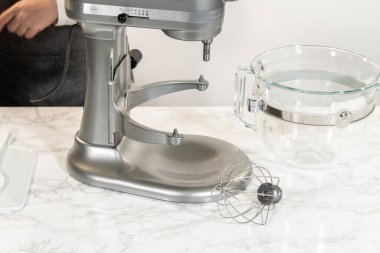 İçinde tereyağı bulunan cam bir karıştırma kabıyla limonlu kurabiye yapmaya hazır bir tezgah hazırlandı. Kablo çırpma eklentisi karıştırma işlemi için hazırlandı.