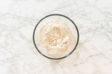 Tek bir kase un, mermer bir yüzeye yerleştirilmiş, Turuncu Zencefilli Kurabiye Kurabiye Tarifi 'nin birincil bileşeni. Un gevşek ve diğerleriyle birleştirilmeye hazır görünüyor.