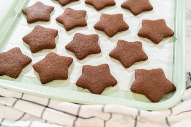 Çikolata yıldızlı kurabiyelerin parşömen kağıdının arka planında yakın plan görüntüsü..