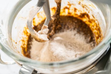 Kuru üzümlü zencefilli kurabiye için mükemmel hamur tatlısı karışımında yavaş yavaş pekmez karışımına katılan kuru malzemelerin yakın çekimi. Un ve baharatlar dengeli bir şey yaratır.