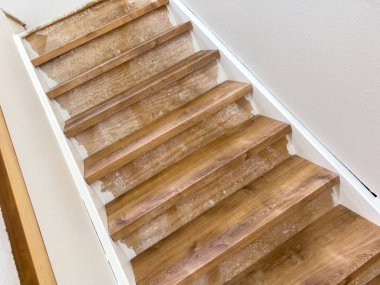 Birkaç merdiven basamağının dar görüntüsü temiz bir kaplama kurulumunu gösteriyor. Kenarları ve köşeleri gevşek ve basamaklar beyaz süpürgelikler boyunca aynı hizada..