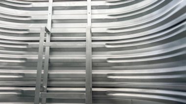 Oluklu çelik bir pencerenin içine yerleştirilmiş metal bir merdiven. Merdiven, konut bodrumundan acil çıkış sağlıyor..