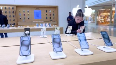 Denver, Colorado, ABD-9 Nisan 2024-10 yaşındaki bir kız dikkatle Apple Store 'daki bir stantta sergilenen yeni bir iPhone' u keşfediyor.