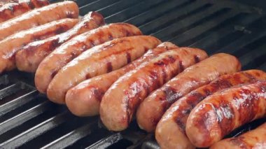 Yavaş hareket et. Sosisler ızgarada kızarırken dumanı serbest bırakır. Sahne, ızgaraya dizilmiş, kahverengileşmeyi ve pişirmeyi ön plana çıkaran çoklu bağlantıları gösteriyor..
