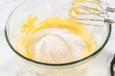 Cam bir kasede taze karışık limonlu kurabiye hamurunun yakın plan görüntüsü pürüzsüz ve tereyağlı dokusunu gözler önüne seriyor. Hamur taze limon lezzeti ve vanilya ile doludur.