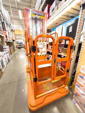 Broomfield, CO, Usa-21 Eylül 2025 - Bir nalbur dükkanının koridorunda içi inşaat malzemeleriyle dolu raflarla dolu turuncu bir merdiven duruyor. Fotoğraf ışıl ışıl parlıyor.