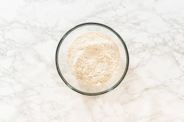 Karıştırma kabındaki un üst görüntüsü, Baharatlı Zencefilli Kurabiye Hamur Pişirme tarifi için mükemmel. Un mermer arka planda duruyor, diğer kuru malzemeler için hazır..