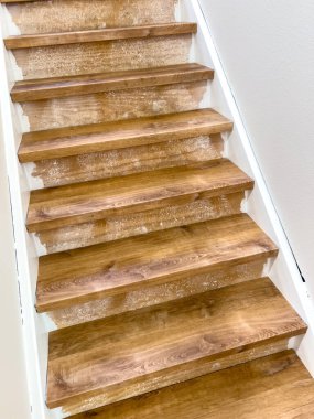 Bir merdiven tamamen ahşap lamine basamaklar ve kenarlar boyunca beyaz süslemelerle donatılmıştır. Sıcak ahşap tonlar, iç mekan ışıklarının altındaki beyaz duvarlarla tamamen tezat oluşturuyor..