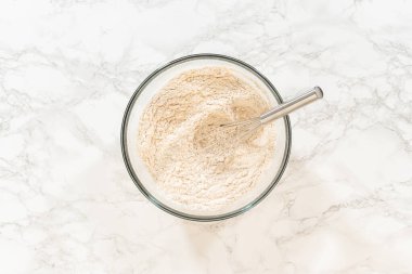 Klasik Zencefilli Kurabiye Hamuru için kuru malzemeler içeren, tarçın, zencefil ve karanfil gibi zengin, koyu baharatlarla dolu bir karıştırma kabının genel görünümü. Baharatlar gözle görülür şekilde katmanlanmış.