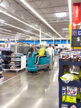 Castle Rock, CO, ABD-12 Ekim 2025 - Castle Rock, Colorado 'da büyük bir perakende mağaza koridorunda çalışan bir zemin temizleme makinesi. İşçi makineyi parlak ışıklı dükkandan geçirir.