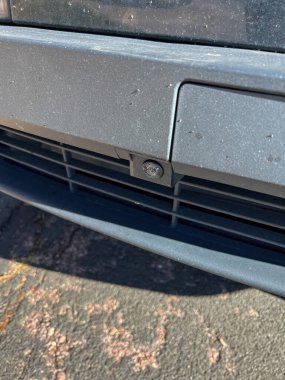 Bir aracın ön tamponunun entegre kamera sensörünü gösteren detaylı bir yakın çekim görüntüsü. Görüntü modern otomotiv teknolojisini vurguluyor, özellikle temiz tasarım ve mat gri kaplama üzerinde duruyor. Şey...