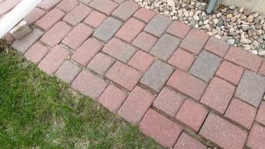 Yavaş hareket et. Kırmızı tuğladan bir bahçe yolu çimenli bir avlunun yanında uzanıyor. Birkaç tuğla yerinden oynamış ya da yerinden oynamış, fark edilebilir boşluklar yaratıyor. Mekan bir yerleşim alanı..