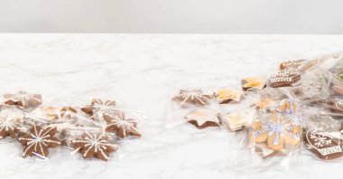 Orta menzilli bir perspektiften yakalanan bir kişi, Noel ağacı şeklinde süslenmiş bir kurabiyeyi dikkatlice paketlerken, yeşil, kırmızı ve zencefilli kurabiyeler de dahil olmak üzere çeşitli ziyafetler sunuyor.