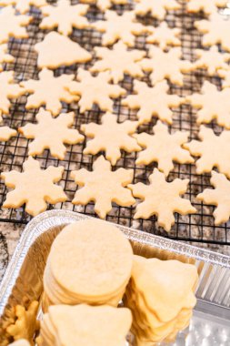 Güzelce hazırlanmış kar tanesi şeklindeki şeker kurabiyelerini folyo tepsisine koyup dondurmaya hazır hale getiriyorlar..