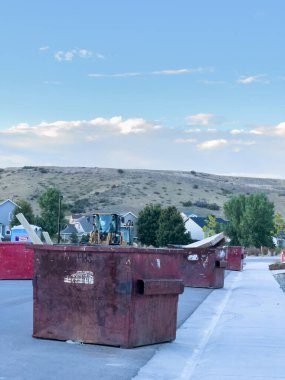 Castle Rock, CO, Usa-21 Eylül 2025 - Slow Motion - Büyük kırmızı çöp konteynerleri Castle Rock, Colorado, ABD 'de bir banliyö caddesi boyunca dizilmiştir. Tepeler ve evler gün ışığında arka planda belirir